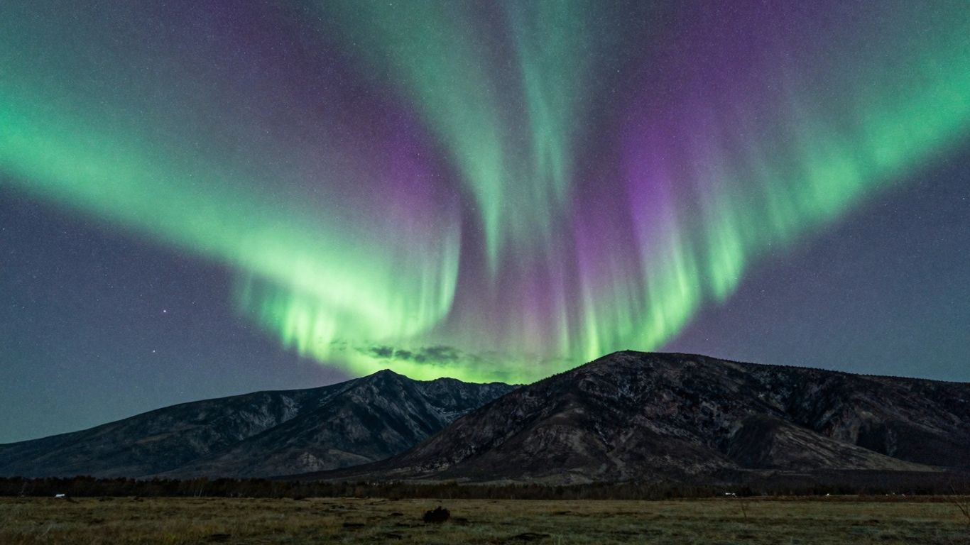 Südliche Lichter über einer Berglandschaft im Sternenhimmel.